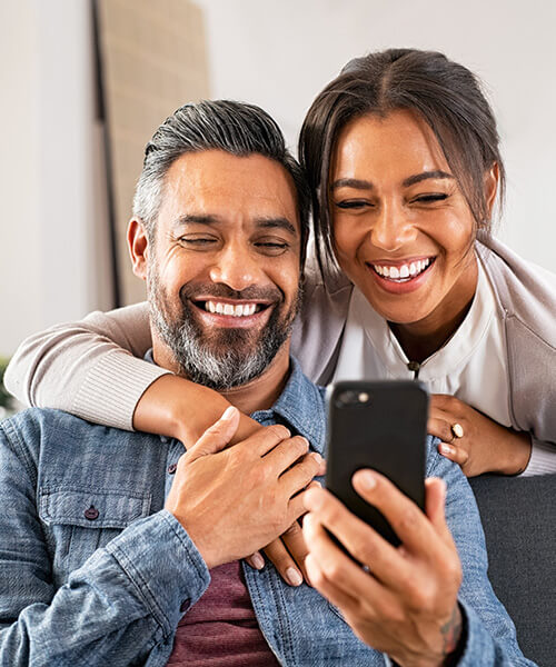 Couple smiling while looking at a phone