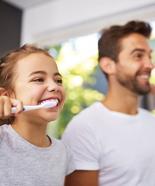 A child with her father brushing teeth