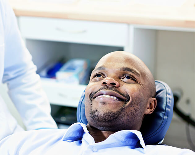 Man on dentist chair smiling thanks to emergency services
