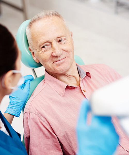 A senior man smiling towards dental assistant