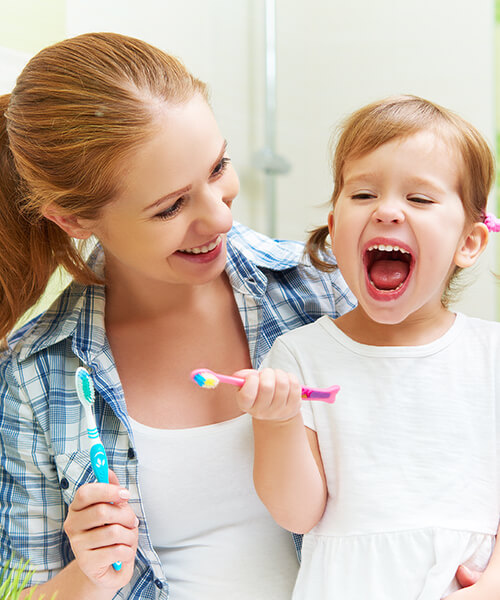 A mother and her child brushing their teeth