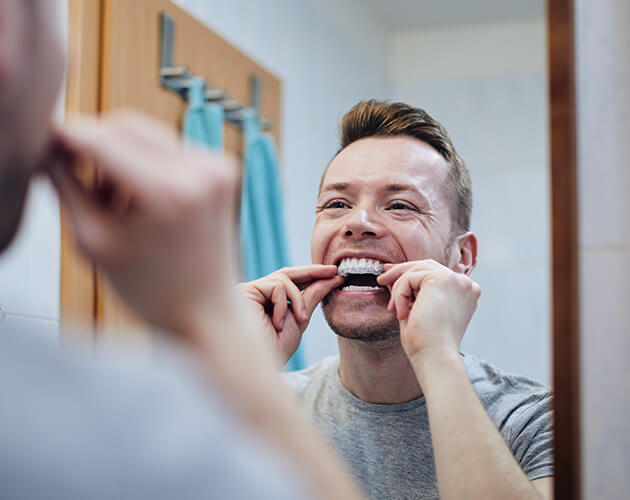 Man Lookig at mirror while putting invisalign on