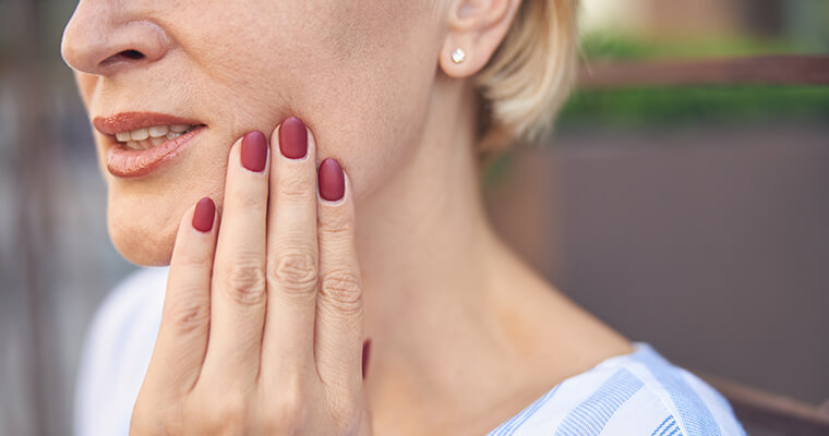 Female holding her cheek in pain with a toothache