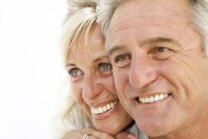 A mature couple with dentures embrace and smile
