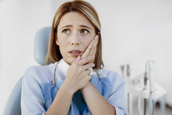 Nervous woman in a dentist’s chair about to receive a root canal treatment