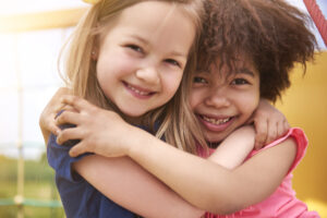 Two young girls hug and smile 