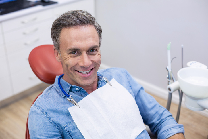 Smiling older gentleman in a dentist's chair after a root canal. 
